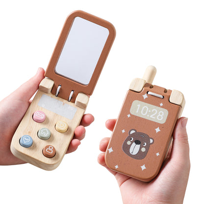 Un bambino tiene in mano un telefono giocattolo, esempio di giochi in legno pensati per l’esplorazione sensoriale.