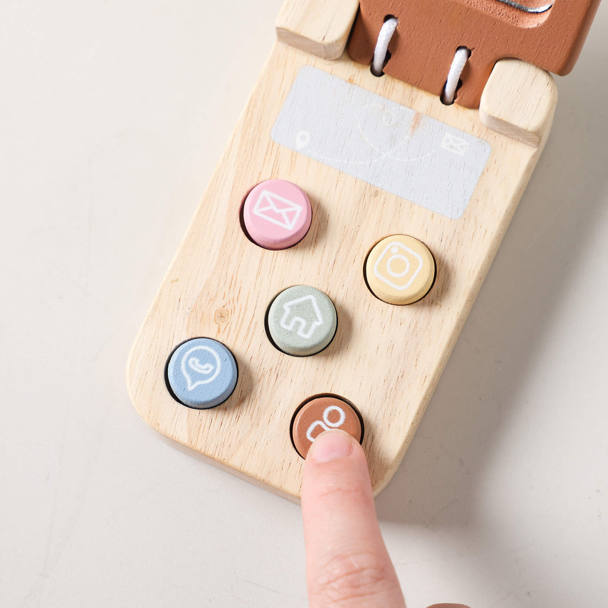 Dettaglio dei tasti colorati su telefono di legno, utili per sviluppare la motricità fine nei giochi in legno educativi.