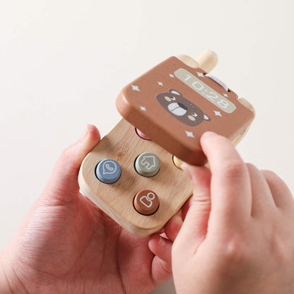 Bambino che simula una telefonata con un telefono in legno, tra i giochi in legno ideali per imitare gli adulti.